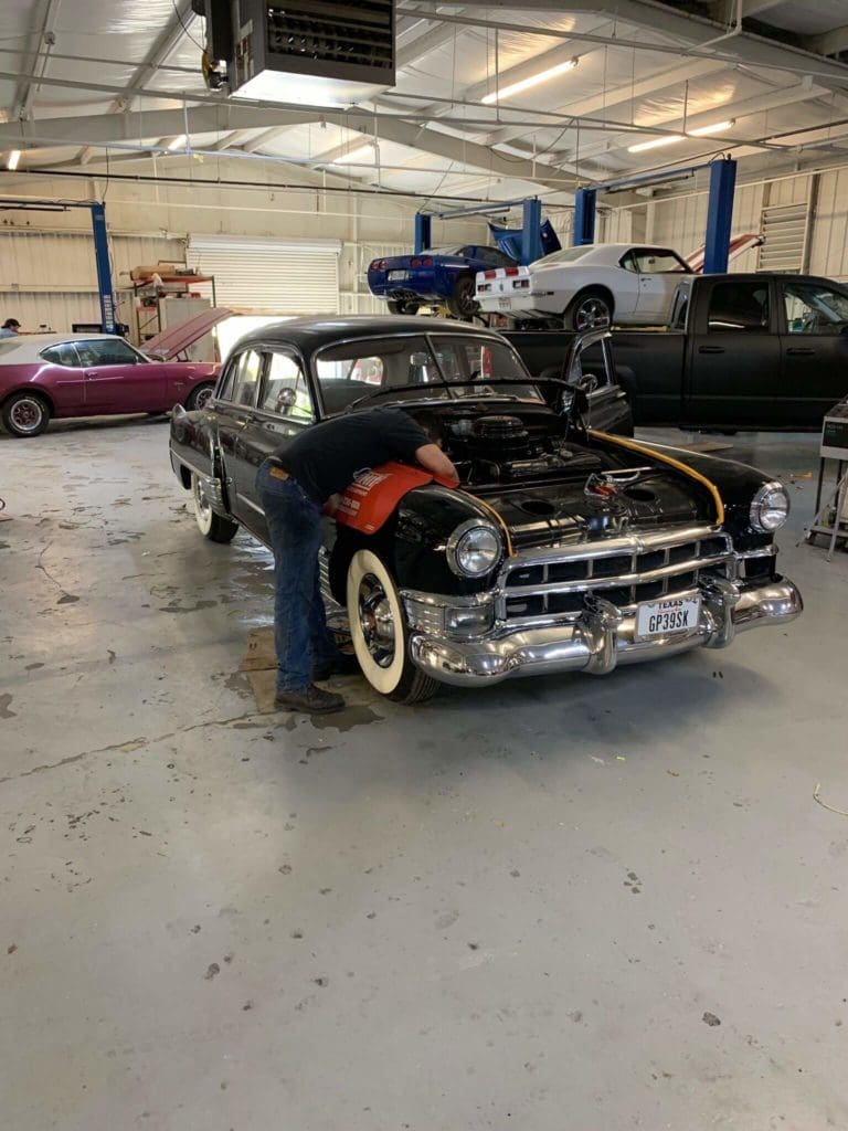 Accelerate Auto Repair technician working under the hood of a car; classic car restoration