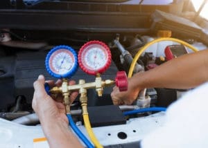 Auto Mechanic at Accelerate Auto Repair using a gauge to test the air conditioner of a vehicle