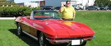 Man standing next to a red car that a custom paint job